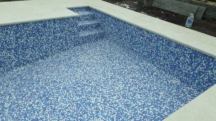 Escalera de piscina revestida en venecita azul y blanca
