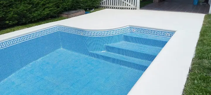 Escalera de ingreso a la piscina con guarda griega en venecita y borde blanco