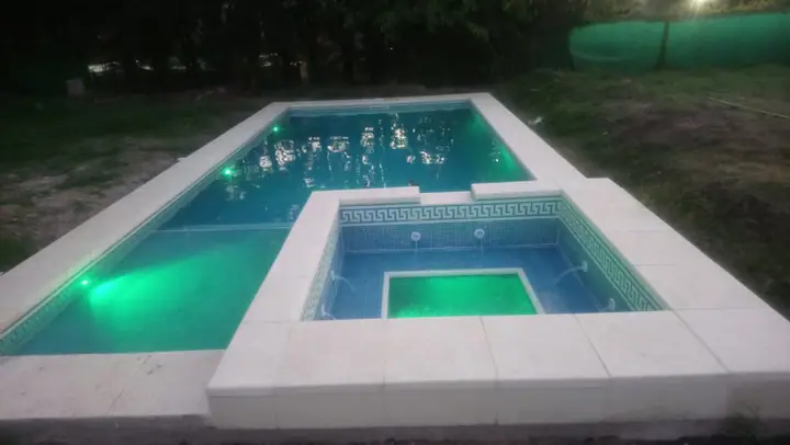 Piscina y jacuzzi elevado de noche con iluminación sumergible verde