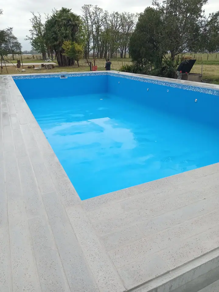 Piscina de 12 por 6 metros pintada, con guarda listón y deck atérmico en el borde