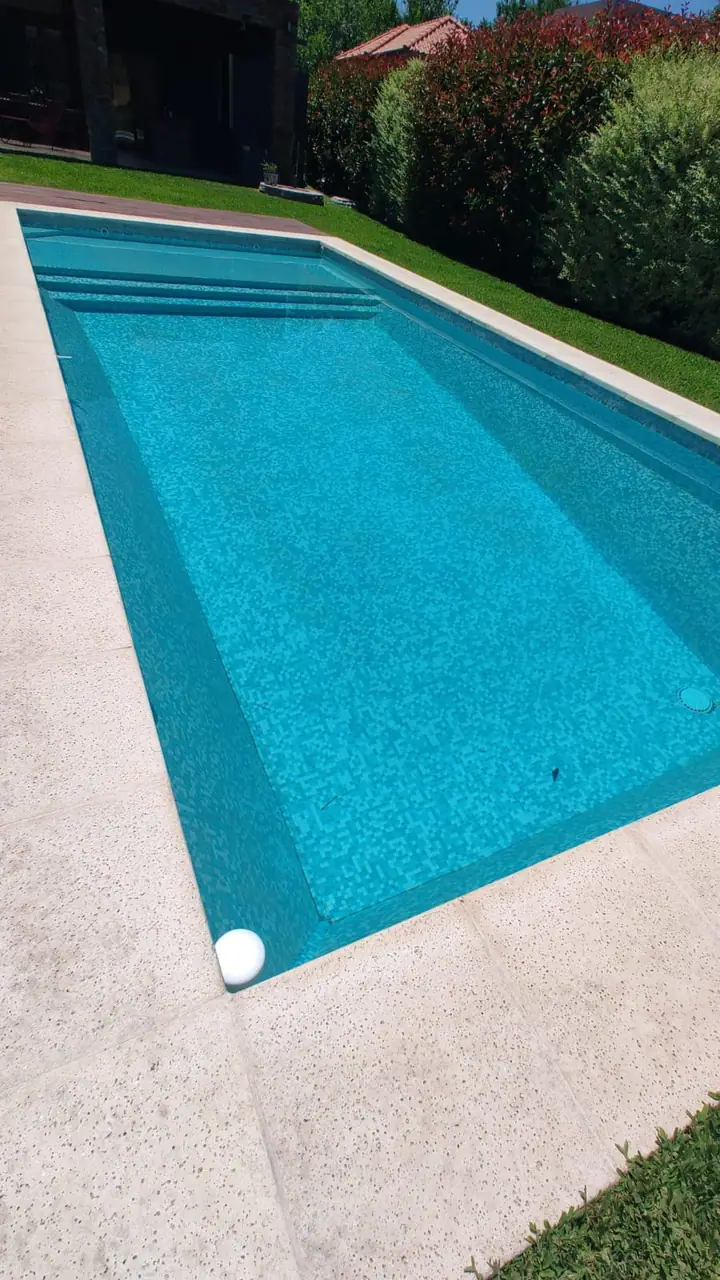 Piscina alargada revestida en venecita azul con borde claro