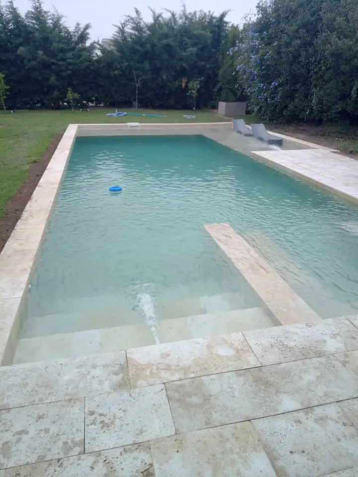 Piscina de agua clara con borde y solárium de placas claras