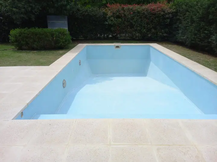 Piscina de interior claro rodeada de cerco verde