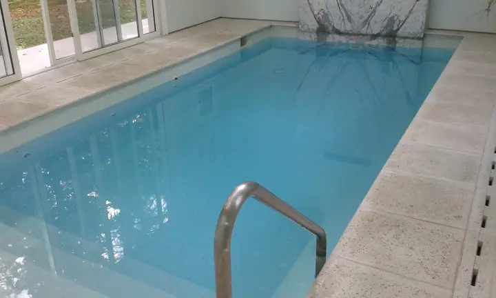 Piscina cubierta con baranda de acero inoxidable y borde claro