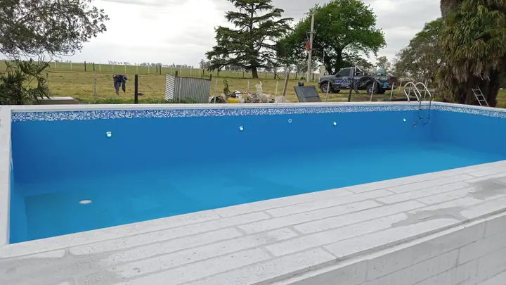 Piscina con deck atérmico perimetral en un terreno abierto con árboles