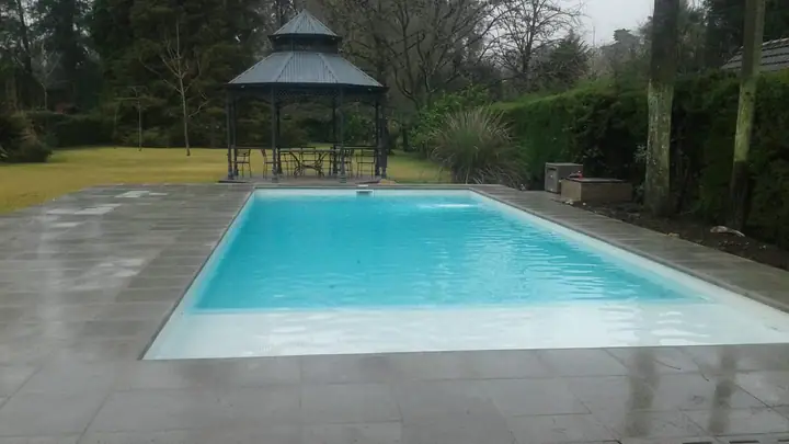 Piscina terminada con deck perimetral y glorieta en el jardín