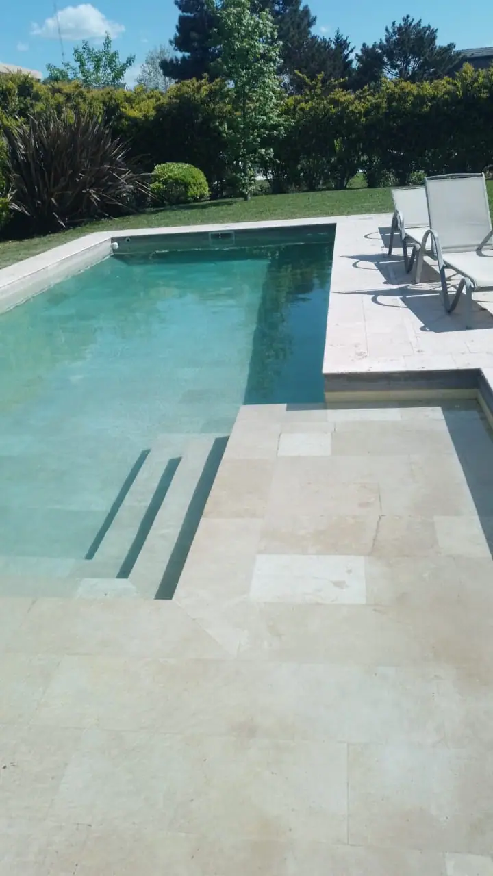 Piscina con escalera de obra y reposeras sobre el solárium