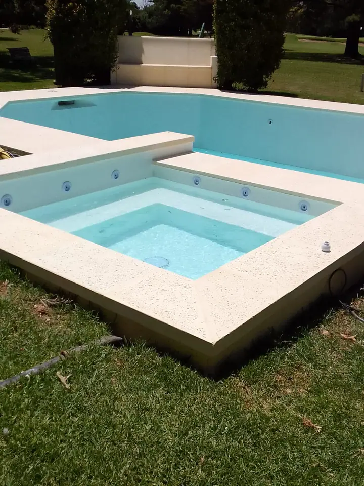 Piscina clara con jacuzzi elevado de hormigón y borde perimetral