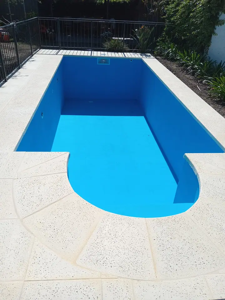 Piscina recién pintada de azul con escalera curva, antes del llenado