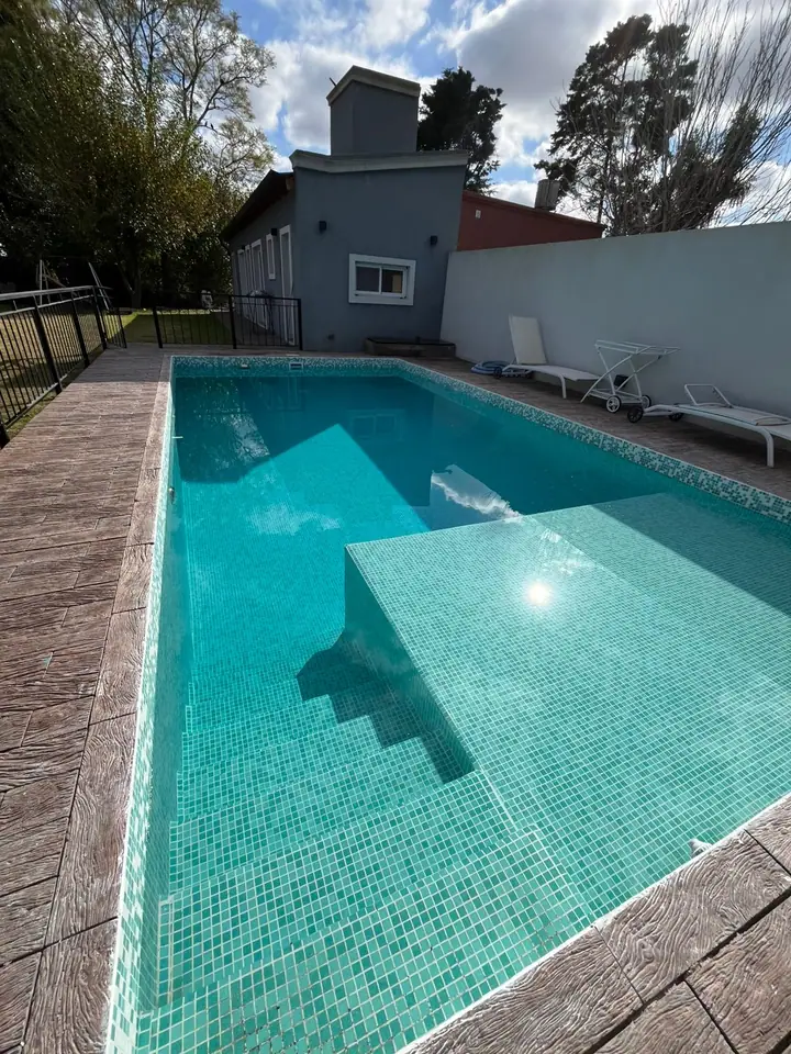 Piscina revestida en venecita con banco sumergido y escalera de obra