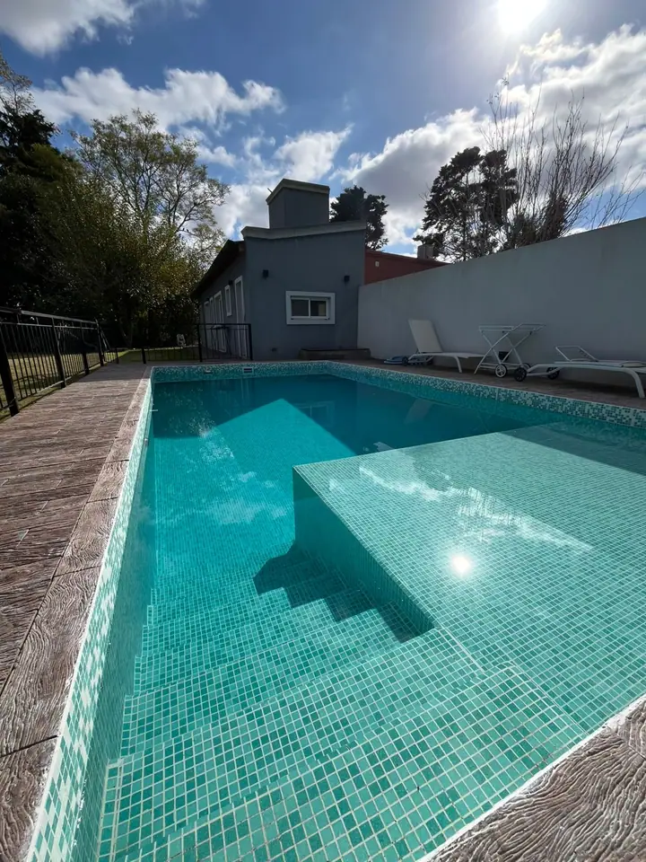 Piscina revestida en venecita con escalera de obra frente a la vivienda