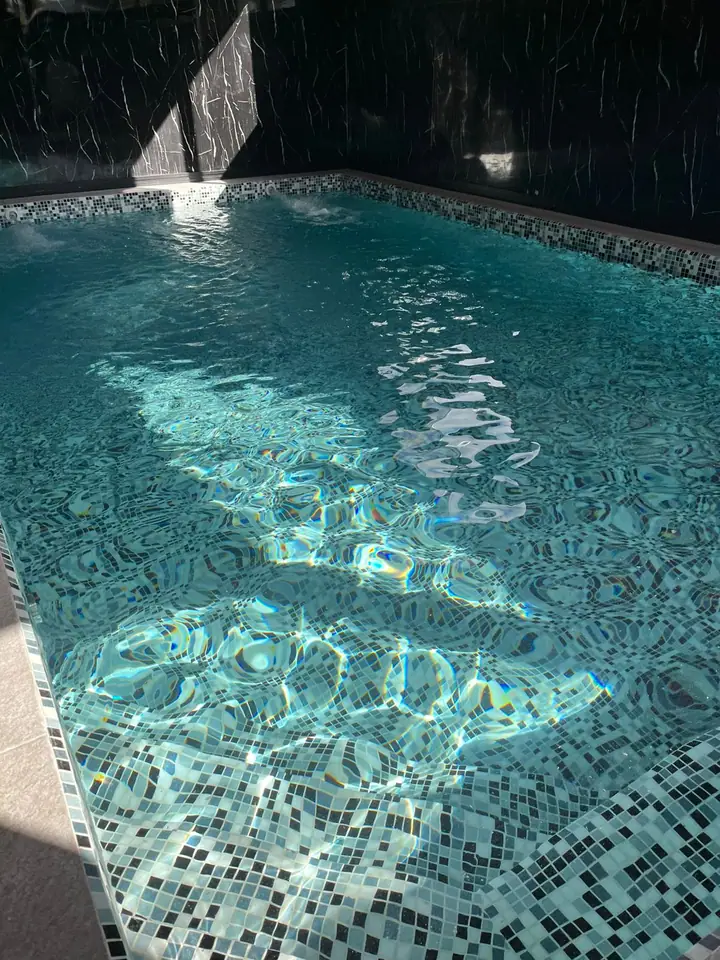 Piscina revestida en venecita gris A150 con reflejos de luz sobre el agua
