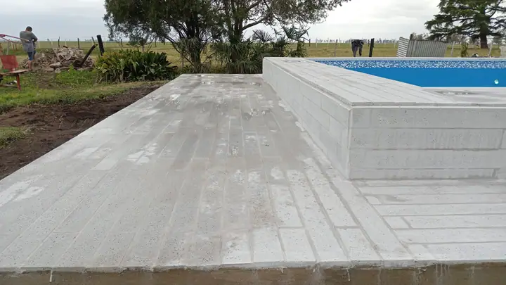 Solárium elevado de placas atérmicas junto a una piscina en entorno de campo