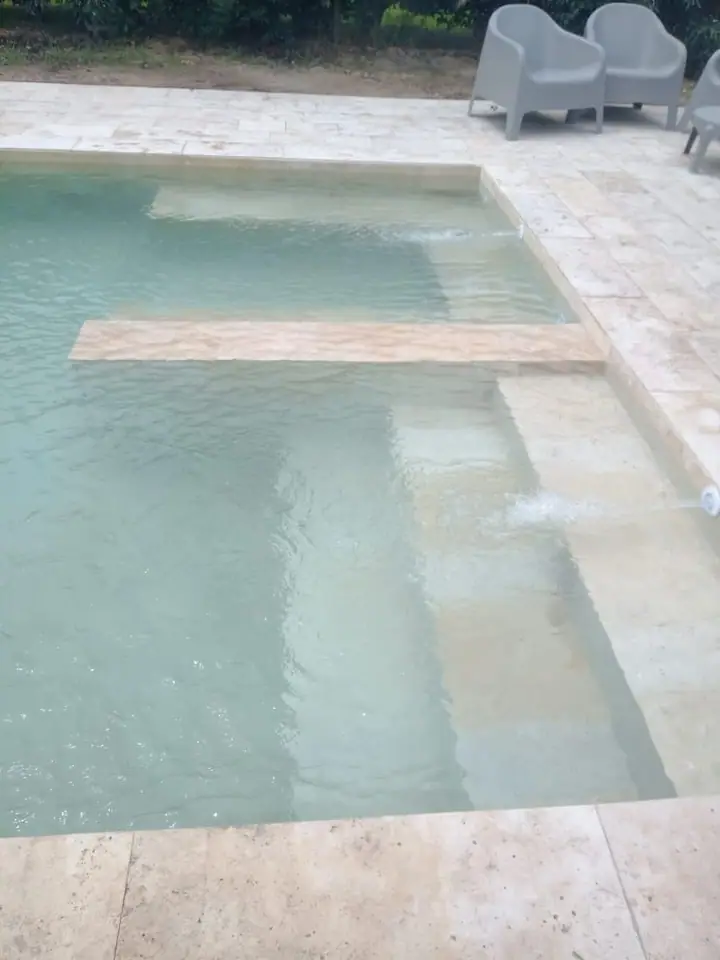 Escalones de ingreso a la piscina con solárium claro