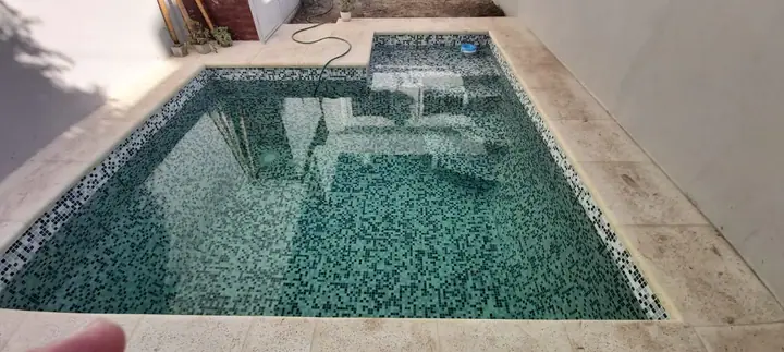 Piscina revestida en venecita verde oscura con borde claro